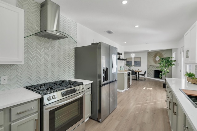 kitchen with stainless steel appliances, wall chimney range hood, light countertops, and visible vents