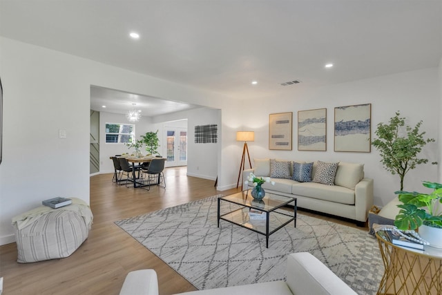 living area with recessed lighting, visible vents, an inviting chandelier, and wood finished floors