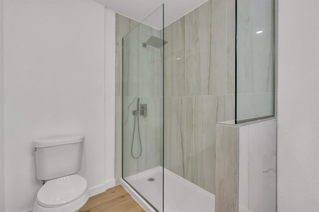 bathroom with a tile shower, wood-type flooring, and toilet