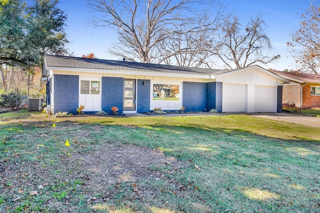 single story home with a front yard, central AC, and a garage