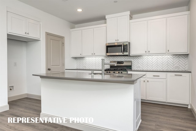 kitchen featuring dark hardwood / wood-style flooring, stainless steel appliances, a kitchen island with sink, sink, and white cabinetry