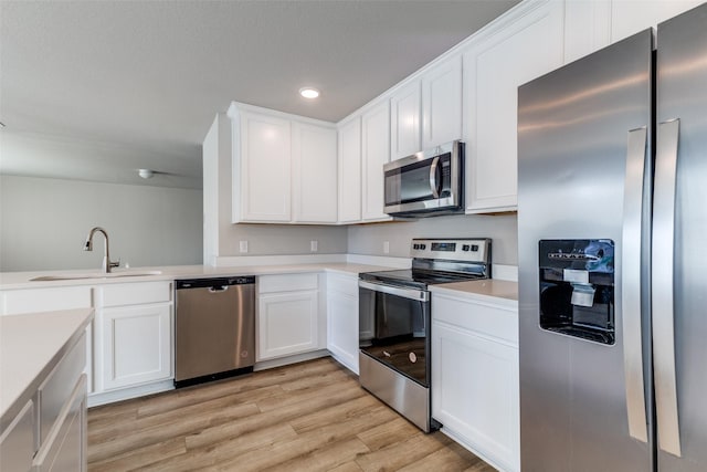 kitchen with light wood-type flooring, stainless steel appliances, white cabinetry, and sink