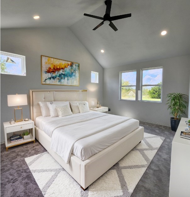 bedroom with ceiling fan, dark carpet, and lofted ceiling