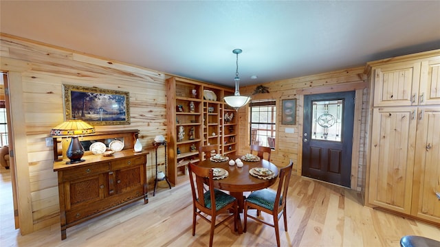 dining room with wood walls and light wood-type flooring