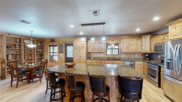 kitchen with sink, a kitchen island, plenty of natural light, and appliances with stainless steel finishes