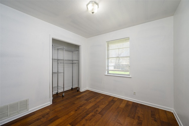 unfurnished bedroom featuring dark wood-type flooring and a closet