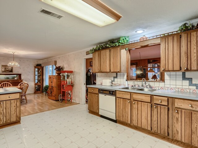 kitchen featuring dishwasher, crown molding, sink, and hanging light fixtures