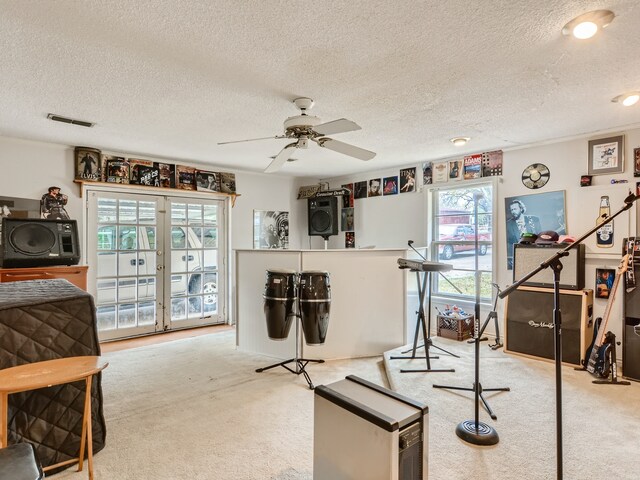 interior space with a textured ceiling, light colored carpet, and ceiling fan