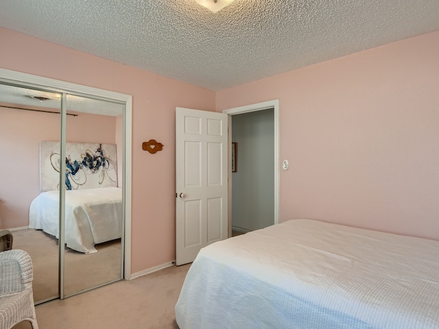 carpeted bedroom with a textured ceiling and a closet