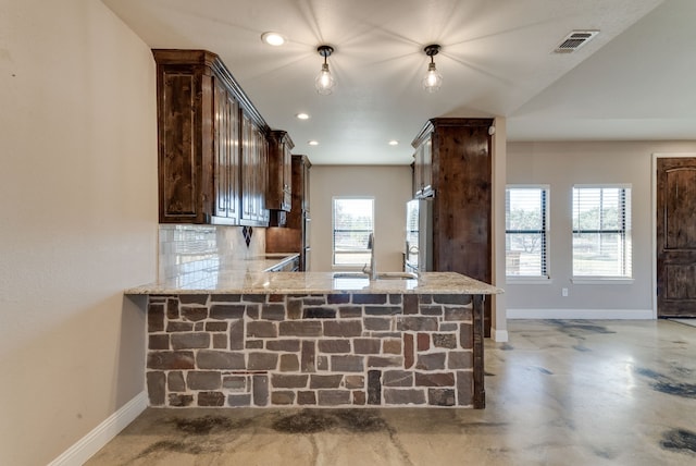 kitchen featuring light stone countertops, kitchen peninsula, sink, and tasteful backsplash