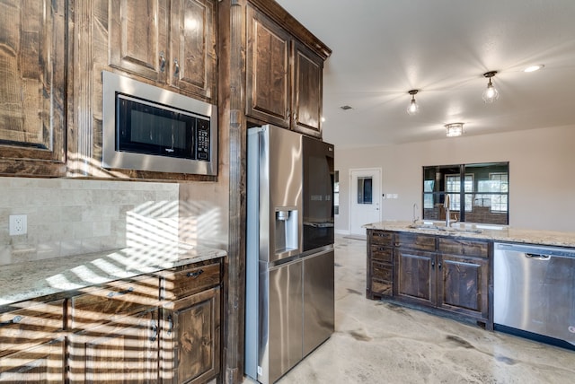 kitchen with dark brown cabinetry, light stone countertops, sink, and appliances with stainless steel finishes