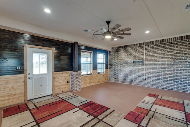 interior space featuring wooden walls, a wealth of natural light, and brick wall