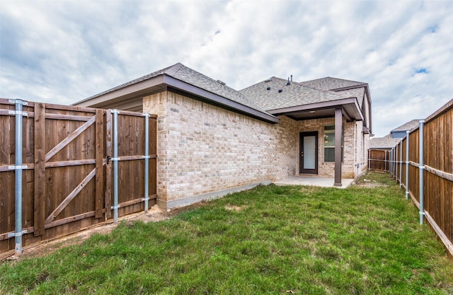 back of house with a lawn and a patio