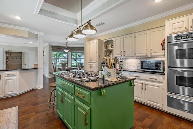 kitchen featuring a kitchen island, appliances with stainless steel finishes, a breakfast bar area, white cabinets, and green cabinetry