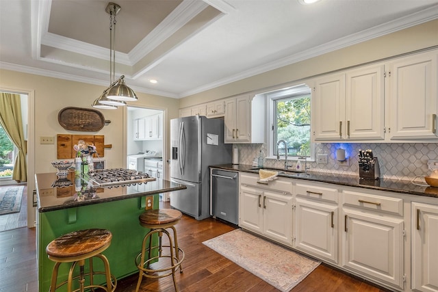 kitchen featuring white cabinetry, a center island, a kitchen breakfast bar, stainless steel appliances, and washing machine and dryer