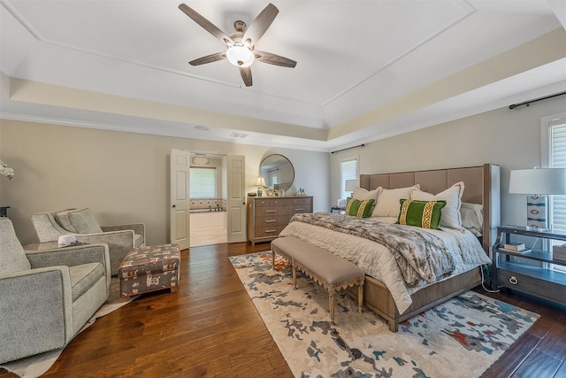 bedroom featuring dark hardwood / wood-style floors, a tray ceiling, multiple windows, and crown molding