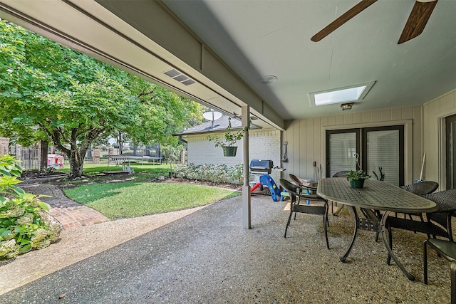 view of patio with ceiling fan, area for grilling, and a trampoline