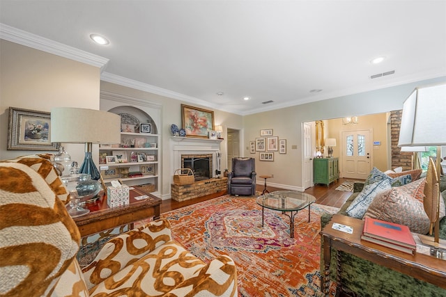 living room featuring crown molding, a fireplace, hardwood / wood-style floors, and built in features