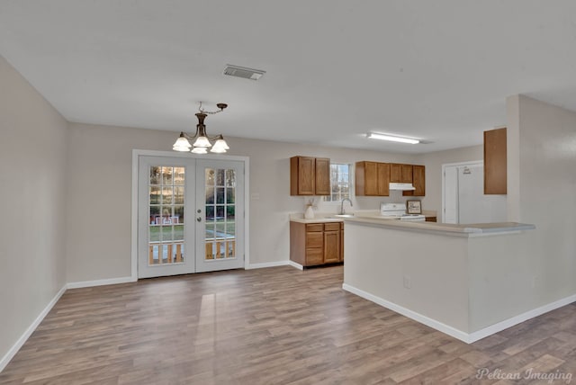 kitchen featuring french doors, sink, hanging light fixtures, light wood-type flooring, and stove