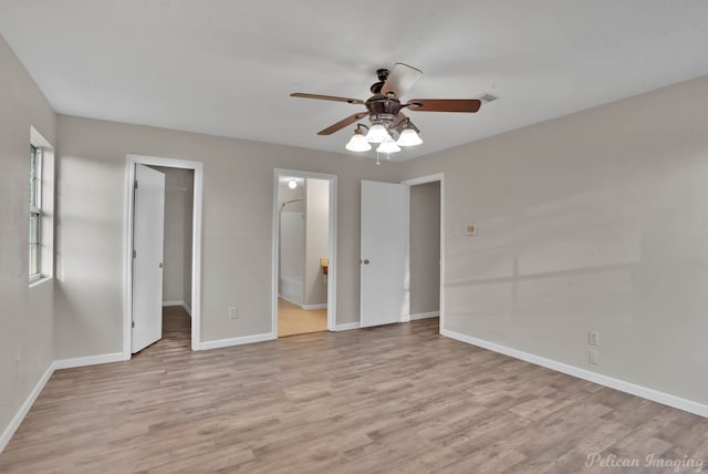 unfurnished bedroom with ceiling fan, a spacious closet, ensuite bath, and light hardwood / wood-style flooring