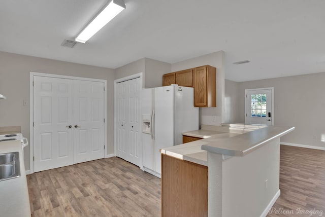 kitchen featuring light hardwood / wood-style flooring, white fridge with ice dispenser, sink, and kitchen peninsula