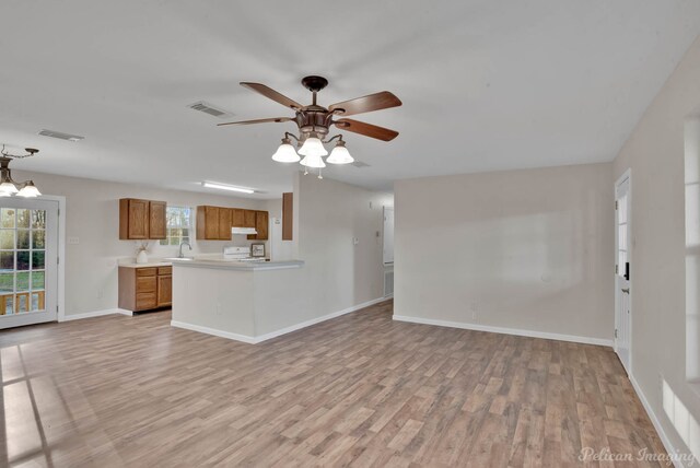 unfurnished living room featuring ceiling fan with notable chandelier, sink, and light hardwood / wood-style floors