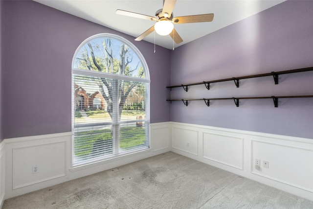 carpeted spare room featuring plenty of natural light and ceiling fan