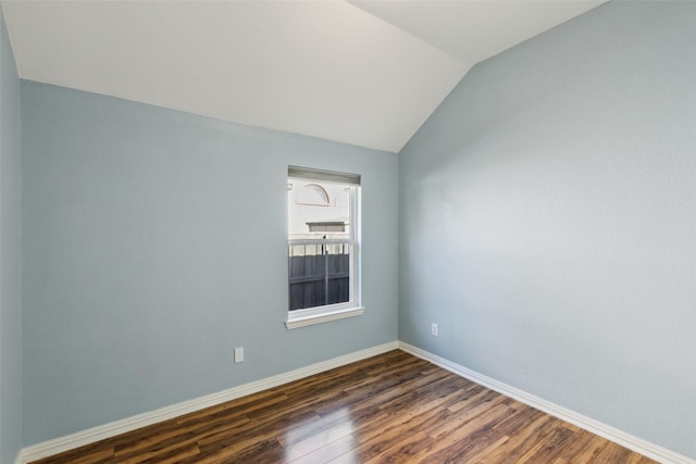 spare room with dark hardwood / wood-style floors and vaulted ceiling