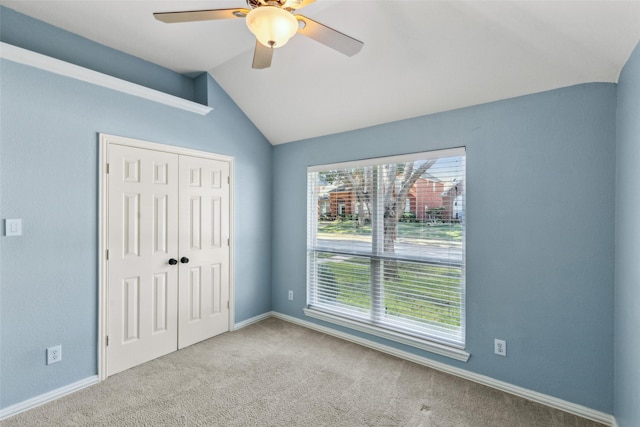 unfurnished bedroom featuring a closet, ceiling fan, lofted ceiling, and light colored carpet