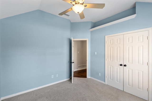 unfurnished bedroom featuring ceiling fan, vaulted ceiling, light colored carpet, and a closet