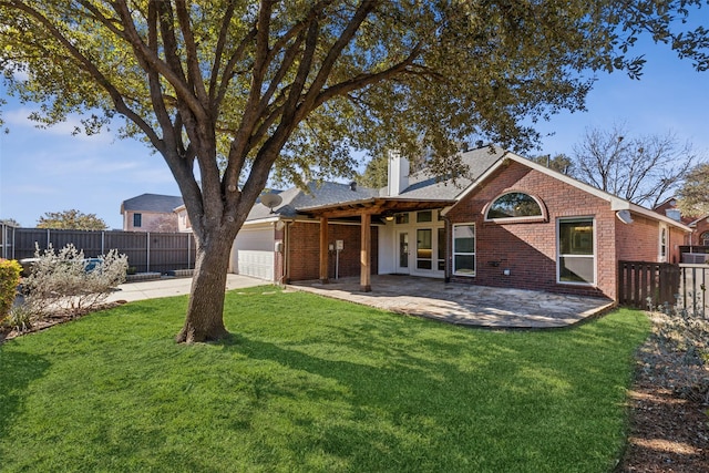 rear view of house featuring a lawn, a garage, and a patio area