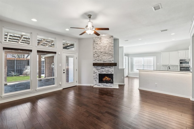 unfurnished living room featuring a fireplace, ceiling fan, and dark wood-type flooring