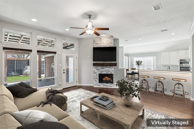 living room featuring hardwood / wood-style flooring, ceiling fan, and a fireplace