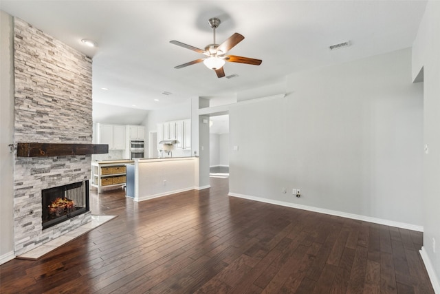 unfurnished living room with dark hardwood / wood-style floors, ceiling fan, a stone fireplace, and lofted ceiling