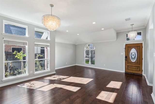 entrance foyer featuring ornamental molding, dark hardwood / wood-style flooring, an inviting chandelier, and a healthy amount of sunlight