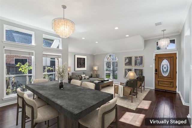 dining area featuring a chandelier, a towering ceiling, dark hardwood / wood-style floors, and ornamental molding