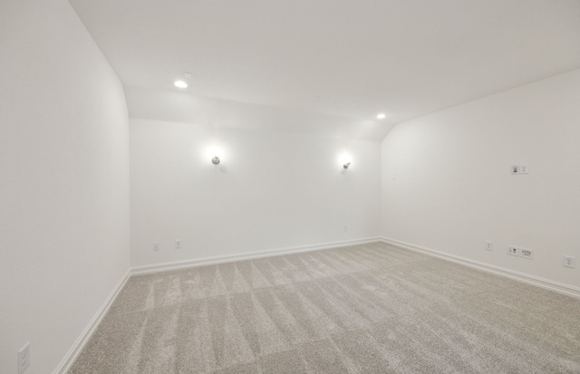 unfurnished room with lofted ceiling, recessed lighting, baseboards, and light colored carpet