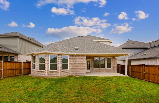 rear view of house with brick siding, a fenced backyard, a lawn, and a patio