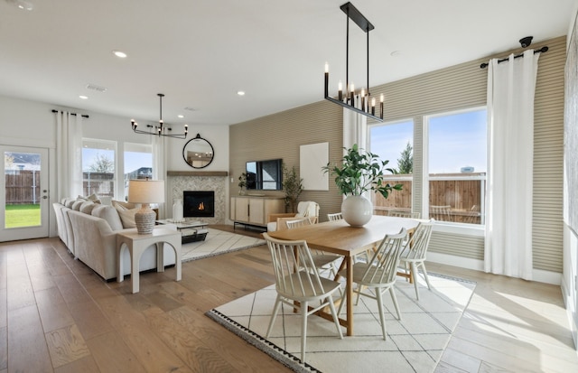 dining room with a chandelier, light hardwood / wood-style flooring, and a tiled fireplace