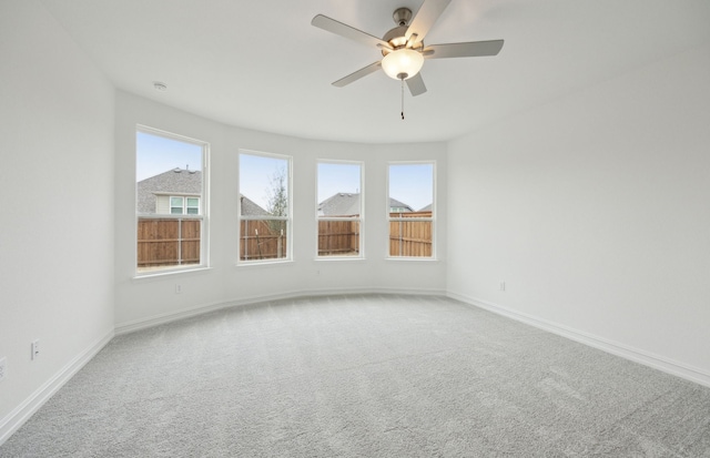 carpeted empty room featuring a ceiling fan and baseboards