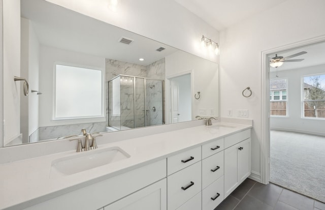 full bath with a marble finish shower, double vanity, a sink, and visible vents