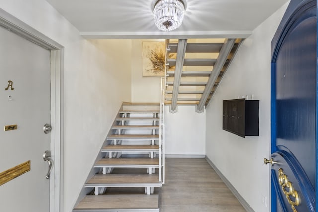 stairs with hardwood / wood-style floors and a chandelier