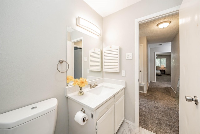 bathroom featuring vanity, a textured ceiling, and toilet