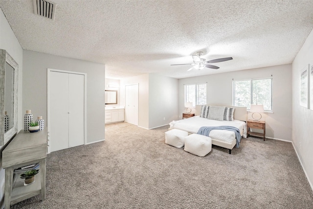 carpeted bedroom featuring ceiling fan, a textured ceiling, and ensuite bath