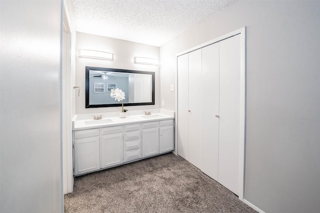 bathroom featuring ceiling fan, vanity, and a textured ceiling