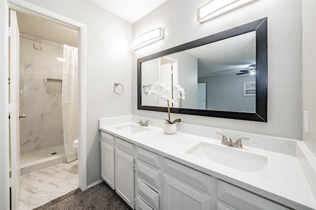 bathroom featuring ceiling fan, vanity, a textured ceiling, and tiled shower