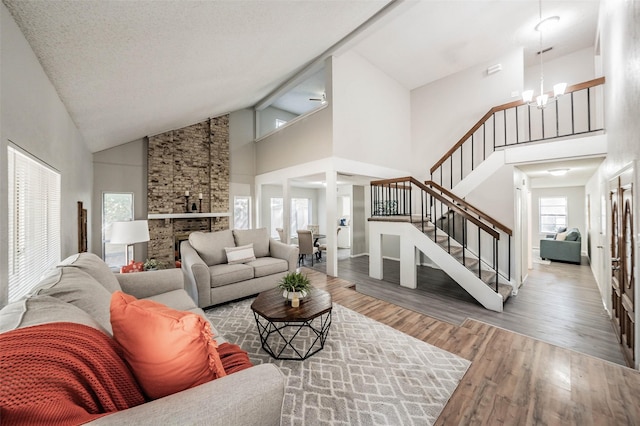 living room with a textured ceiling, high vaulted ceiling, a notable chandelier, and hardwood / wood-style flooring