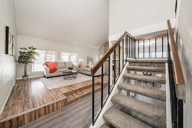 stairs with high vaulted ceiling and hardwood / wood-style flooring