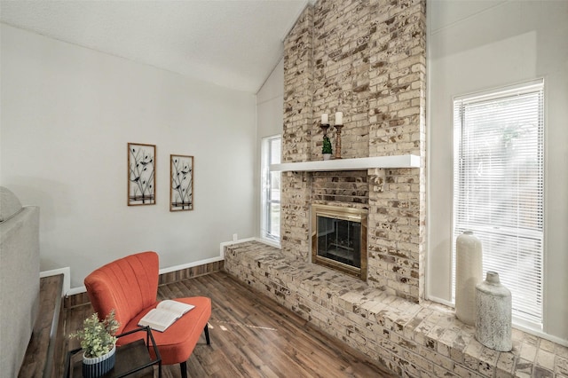 unfurnished living room with a fireplace, dark hardwood / wood-style floors, high vaulted ceiling, and plenty of natural light