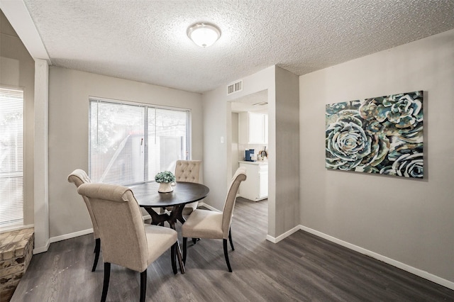 dining space with dark hardwood / wood-style floors and a textured ceiling